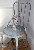 Vintage metal chair with flowers in glass vase