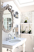 Bright wash area with mirror and orchids on a white shelf