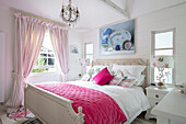 Country-style bedroom with pink bedspread, chandelier and picture