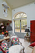 Living room with high window, colorful accent cushions and red door