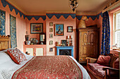 Schlafzimmer mit antikem Schrank, Kamin und blau-roter Dekoration