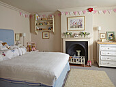 Double bed in cream-coloured room with fireplace, pennant chain above