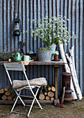 Rustic garden table with flowers, branches and antique lantern on the wall