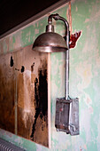 Vintage metal sconce on a wall with peeling paint