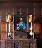 Antique wooden chest with porcelain lamps, above it portrait painting