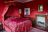 Dramatic four-poster bed in red damask in bedroom with red wallpaper