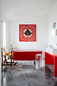 Red accessories in a bathroom with white walls and concrete floor