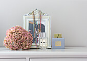 Dried hydrangea next to perfume bottles on a white chest of drawers