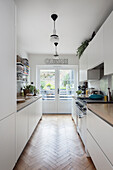 Bright kitchen with white cabinets and herringbone parquet flooring