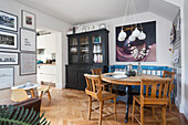 Dining area with round wooden table and chairs, picture wall and display cabinet