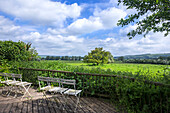 Terrasse mit weißen Klappstühlen und Blick auf grüne Landschaft