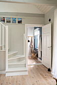 Hallway with coat rack, wooden staircase and floorboards in a bright room