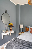 Schlafzimmer mit blaugrauen Wänden, weißem Wandregal und herbstlichem Blumenstrauß