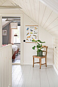 Dachgeschoss-Schlafzimmer mit Poster und Holzstuhl mit Zimmerpflanze