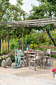 Wooden table and chairs under pergola on deck in summer