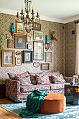 Patterned sofa and oval stool in front of a wall with portrait frames and leopard print wallpaper