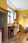 Küche im Vintage-Stil mit gelber Wand, Musterfliesen und Holzmöbeln
