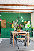 Dining area with green wall, wooden table and coffee house chairs