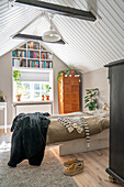 Bedroom under sloping ceilings with bookshelf and plants