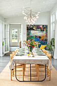 Brightly coloured dining area with flower arrangement and artwork