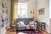 Colourful living room with bookshelf, patterned rug, blanket and decorative cushions