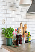 Kitchen worktop with utensils, spices and pot of basil