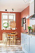 Kitchen with terracotta-coloured walls, dining table, chairs and hanging lamp