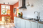 Kitchen with light-coloured fronts, metro tiles and terracotta walls