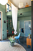 Living room with high ceiling, blue chair and green plants