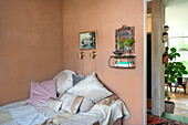 Bedroom with terracotta walls, shelf, picture, mirror and bed with lots of pillows