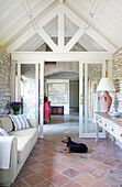 Bright living room with exposed ceiling beams and terracotta floor, dog