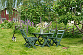 Green wooden garden furniture in front of flower bed with cat in summer garden