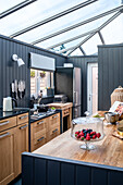 Kitchen with glass roof, wooden cabinets and dark blue walls