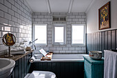 Badezimmer mit Badewanne, weißen Fliesen und schwarzer Holzverkleidung