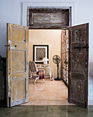 Rustic double doors open to a living room with vintage furniture and fan