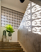 Staircase with decorative concrete wall and shadow play, vases on pedestal