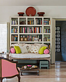 Living room with bookshelf, built-in bench and colorful pillows