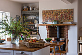 Landhausküche mit Esstisch, Kamin, Obstkorb und dekorativem Blumenarrangement