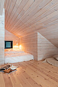 Gemütliche Dachkammer mit hellem Holz und Doppelbett
