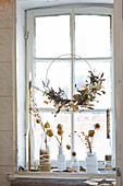 Wreath of dried flowers and vases with dried flowers on the window