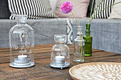 Candle lanterns and pompom dahlia in glass vase on wooden table