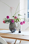 Blumenarrangement mit Pompom-Dahlien in grauer Vase auf Esstisch