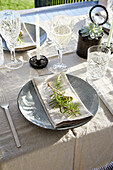 Outdoor dining table with crystal glasses and sprigs of rosemary