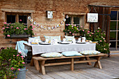 Festive table setting in front of a farmhouse with geraniums