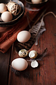 Eggs, quail eggs, and feathers on a wooden table