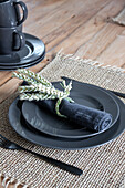 Place setting with dark grey plates and homemade wheat stalk napkin ring