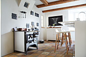 White kitchen with modern bar stools at the counter and antique cooker