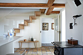 Floating staircase in room with white walls and rustic tiled floor