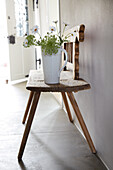 Jug with flowers on a wooden bench in the hallway