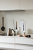 Minimalist kitchen unit with kettles, cutting board and utensils